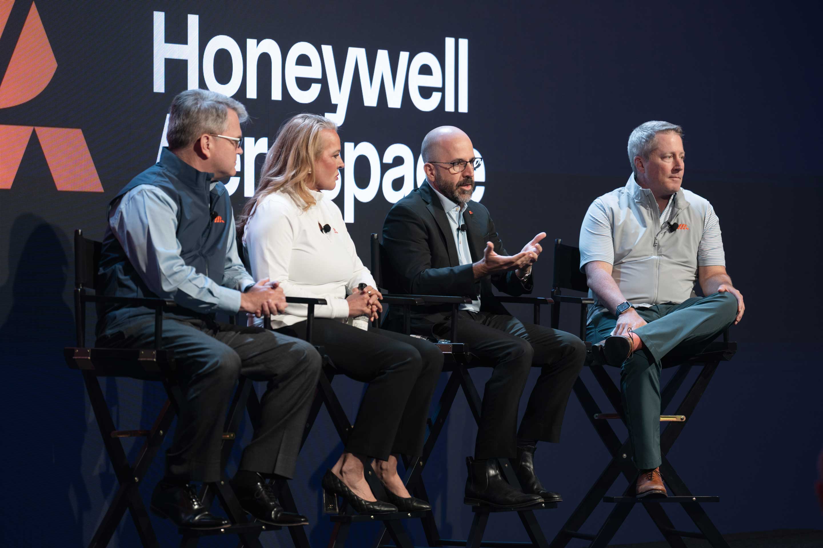 Panel of speakers seated on stage participating in a discussion with Honeywell Aerospace backdrop.