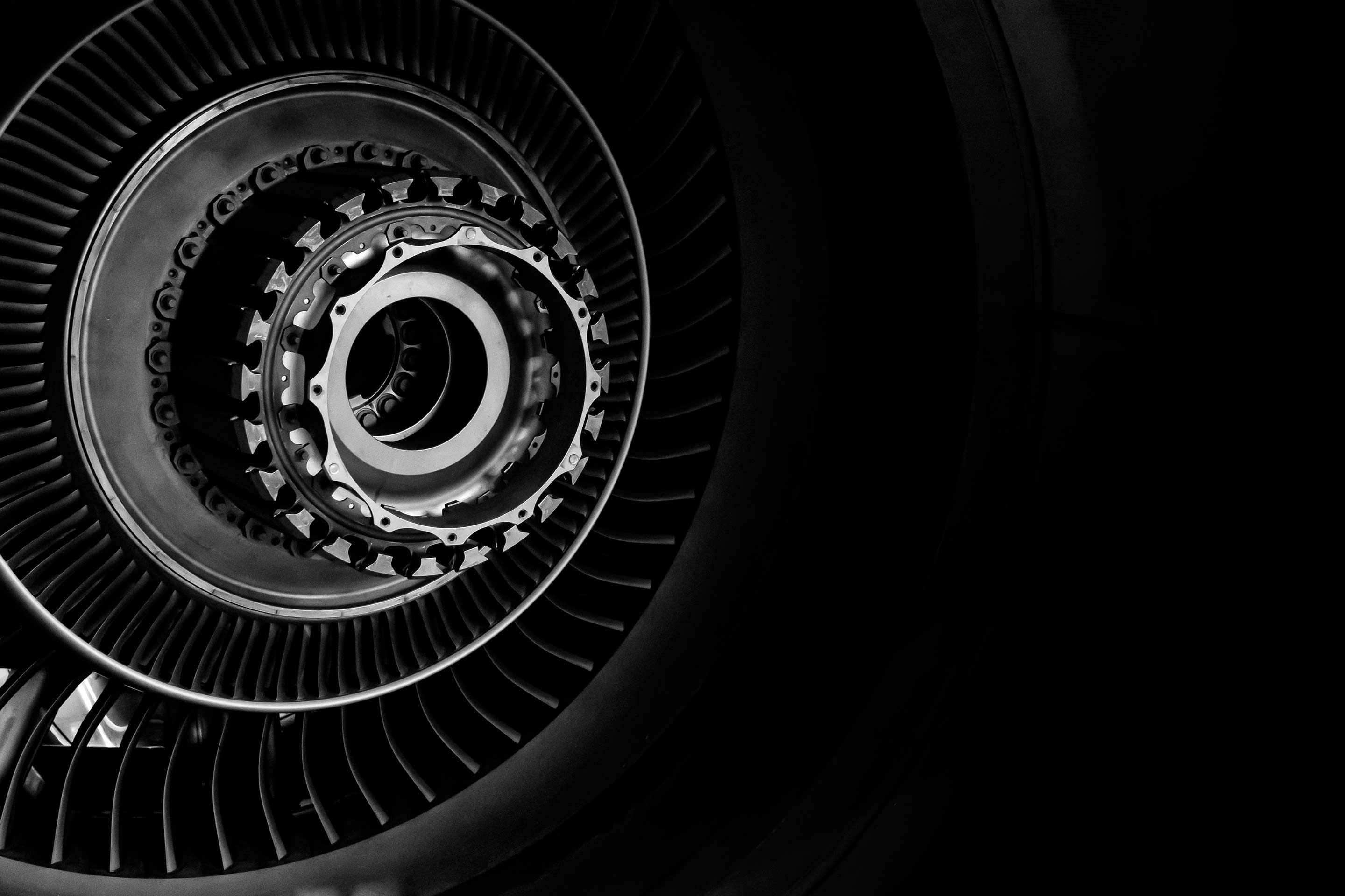 High-contrast black and white view of a jet engine turbine core, highlighting layered blades and precision engineering in a circular composition