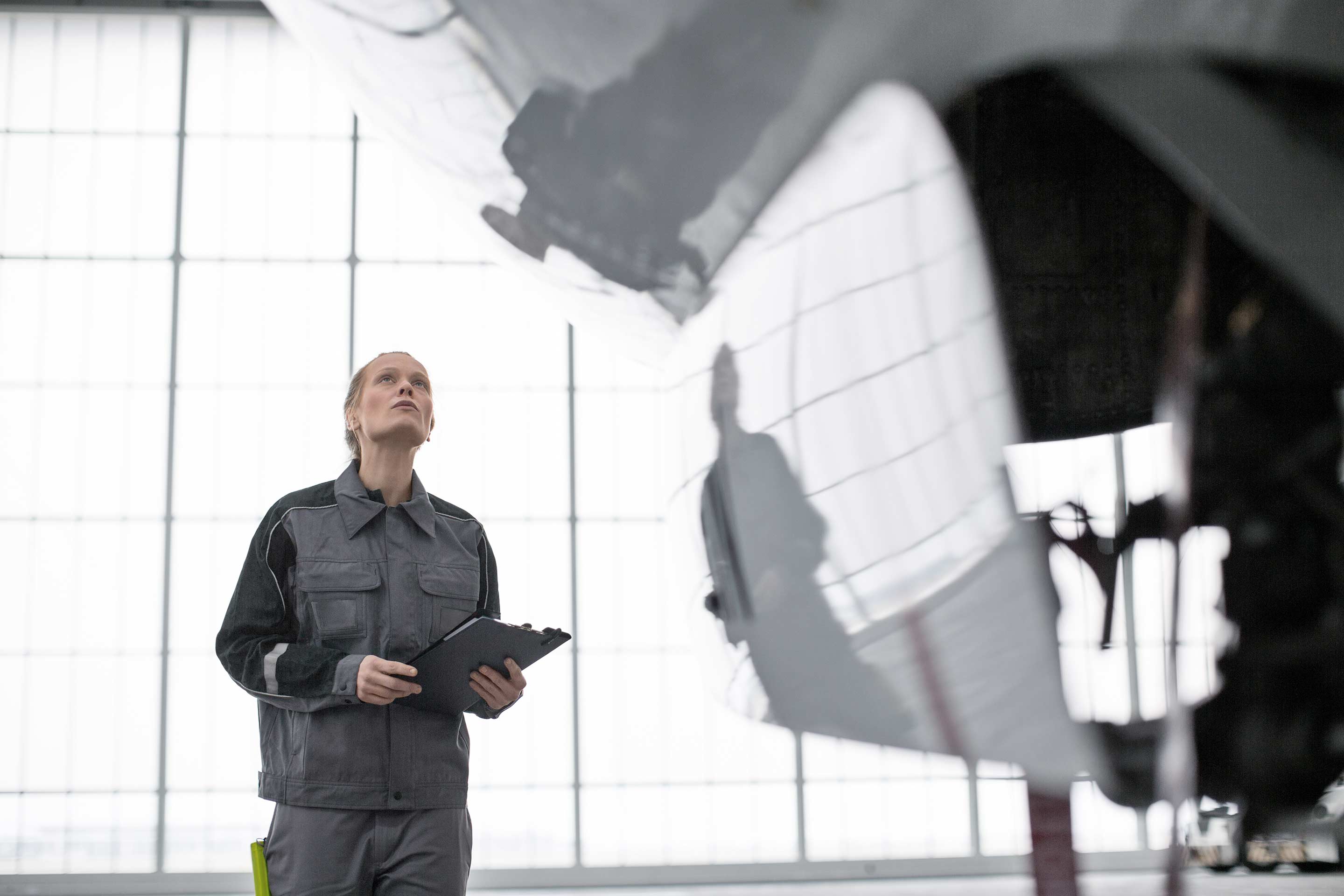 Aviation professional holding a tablet while standing beside an aircraft inside a hangar.