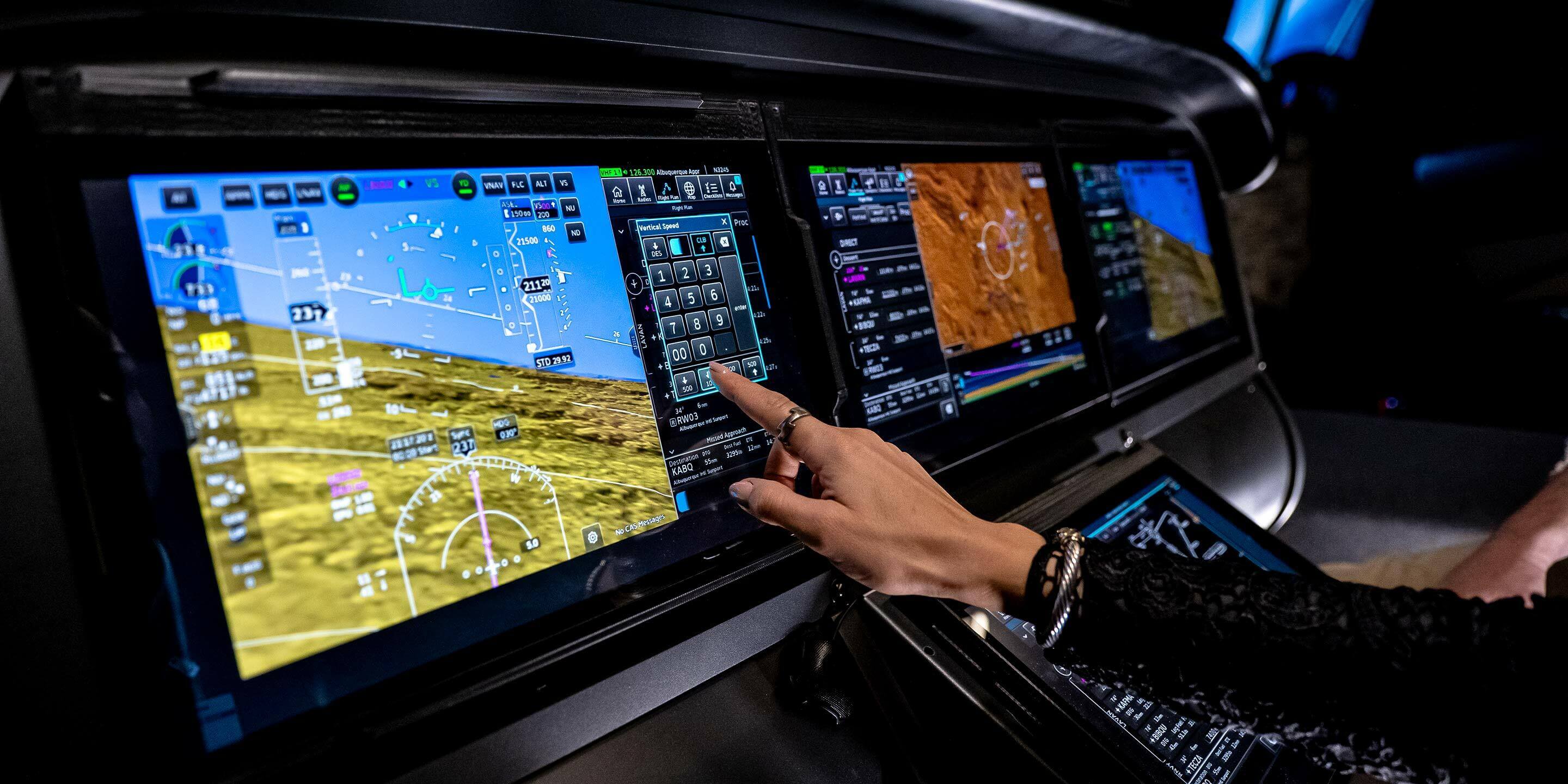 image showing a person pointing at a cabin monitor with three screens