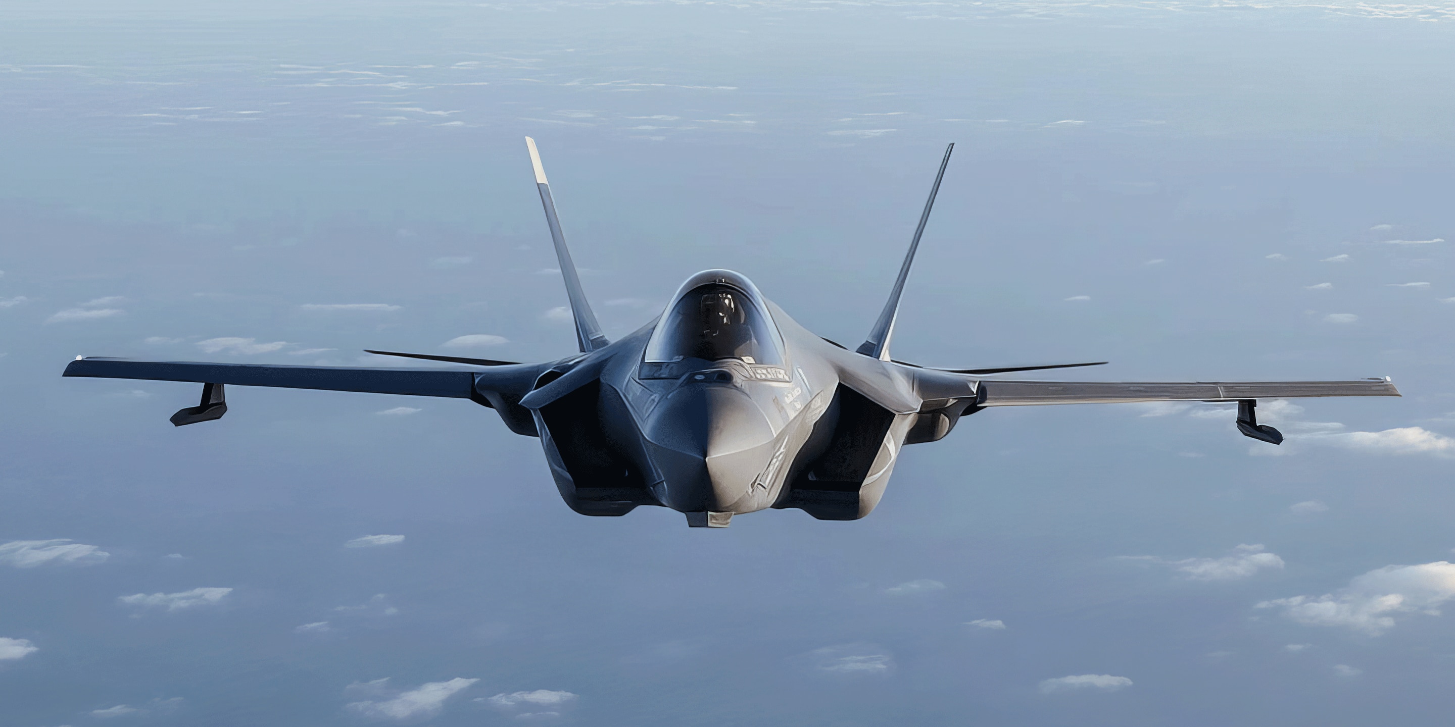 image of a a military fighter jet in flight against a backdrop of clouds in a clear sky