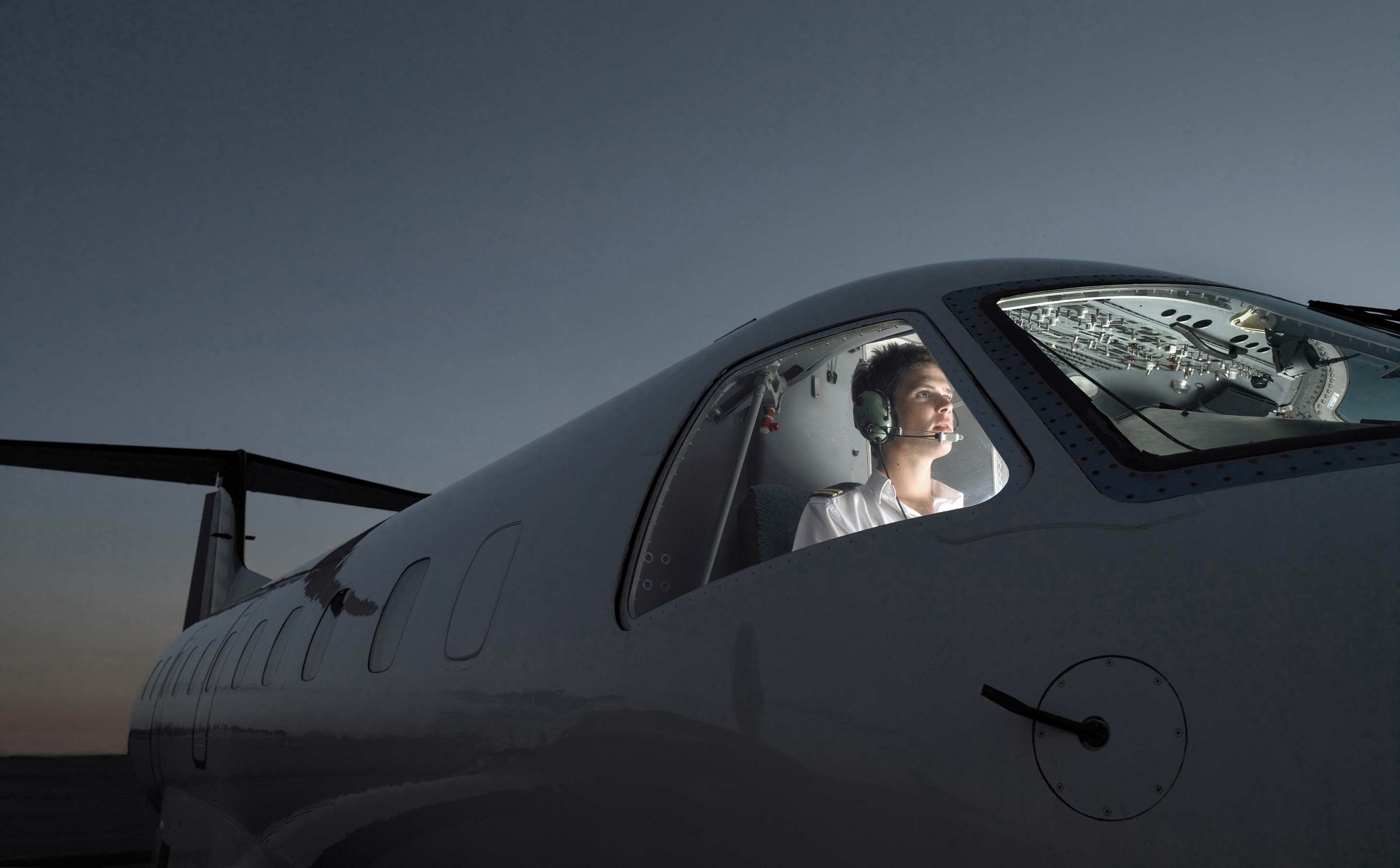 Pilot wearing headset inside modern jet cockpit